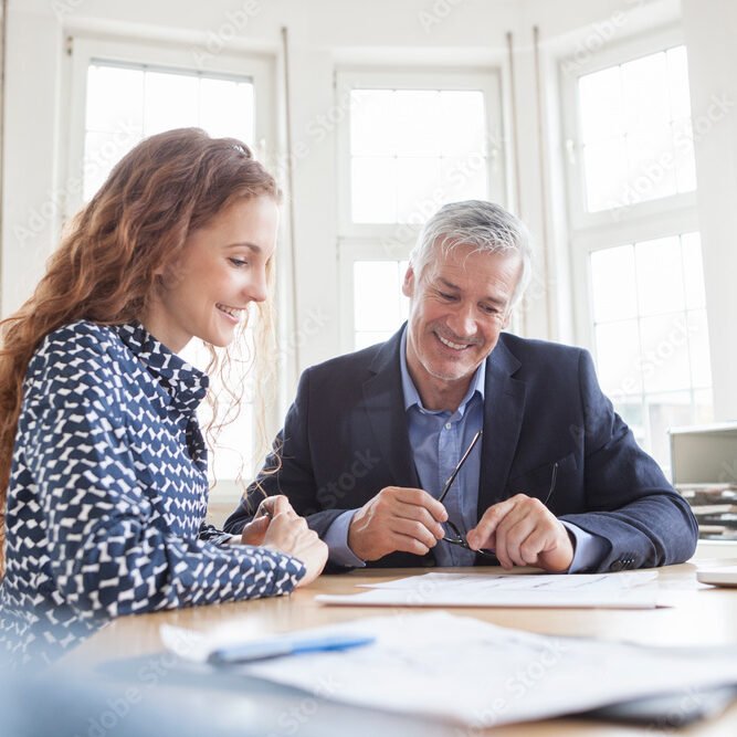 Businessman and woman at desk discussing plans